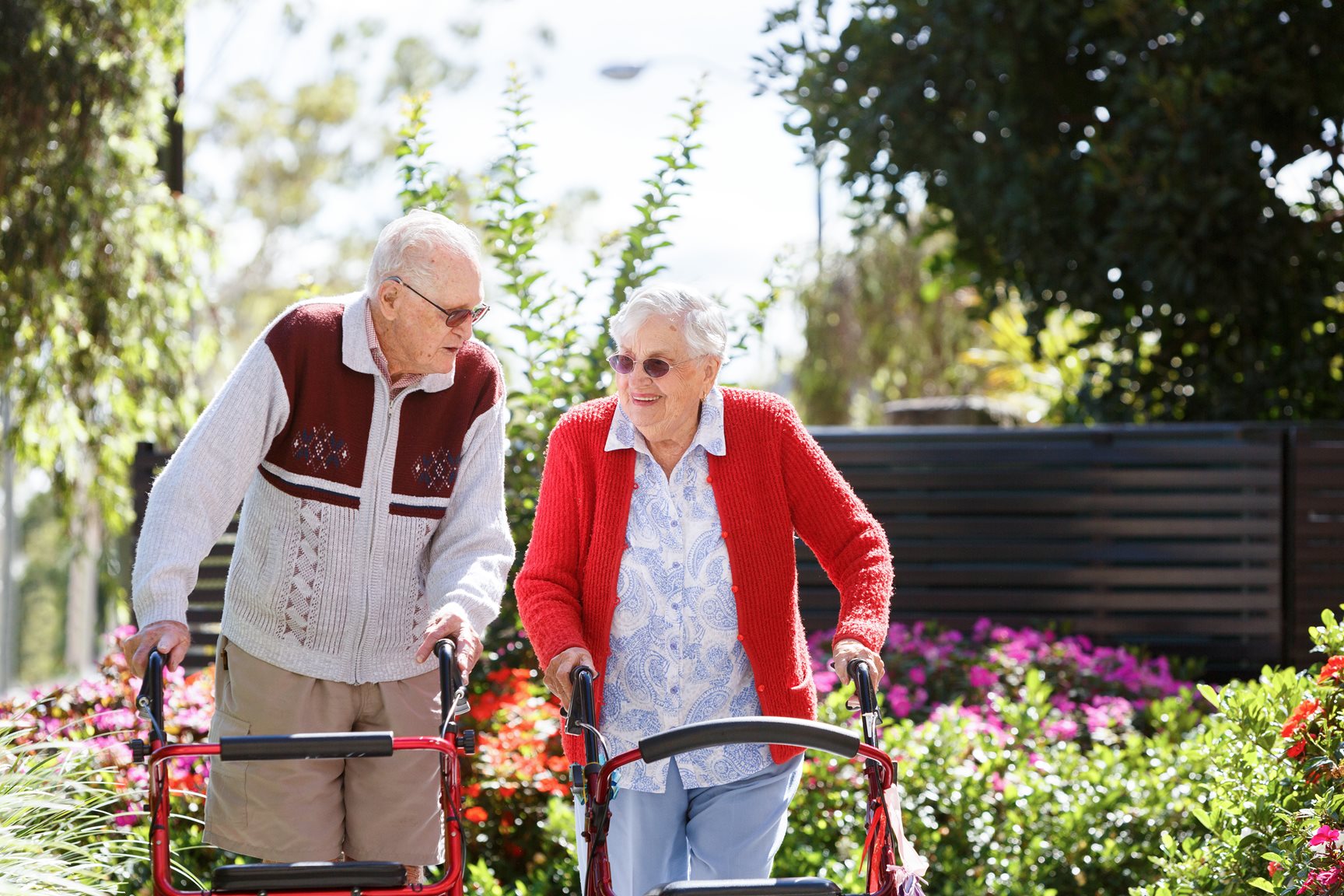 two aged care residents walking through a garden together